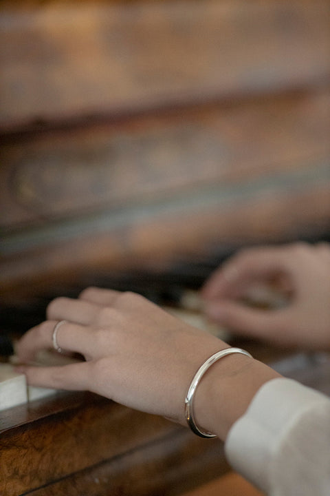 A minimalist bracelet crafted from a rigid silver tube with a distinctive semi-circular cross-section. Clean, elegant, and architectural, it offers a refined statement that complements both everyday and elevated styling. Discover timeless simplicity and modern form by UMIAR jewelry.