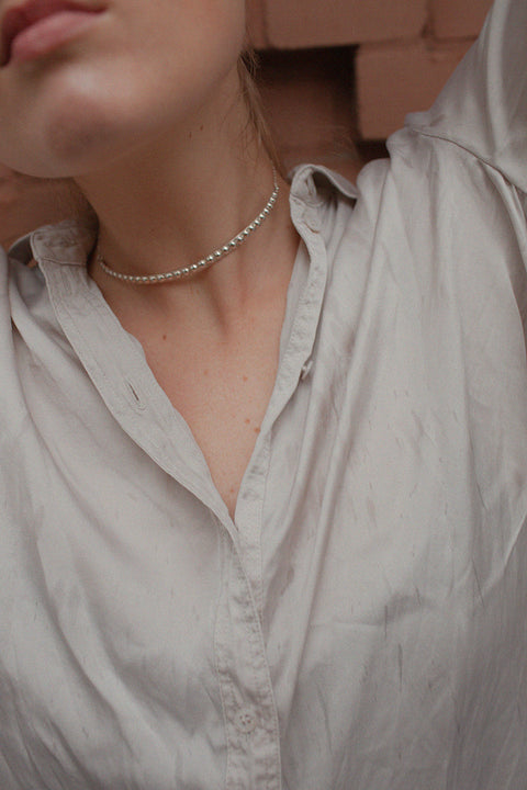 A decorative choker necklace featuring a studded half-hoop and adjustable length for a perfect fit. Elegant yet flirtatious, it highlights the neck and décolletage with refined character. With a total length of 40 cm, it adapts effortlessly to various styling needs. Discover expressive elegance by UMIAR jewelry.