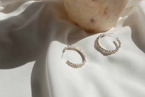 Large hoop earrings inspired by the sculptural surface of the moon, featuring a speckled, textured silver finish. With a 30 mm diameter, their irregular granulated structure reflects light beautifully, creating a bold yet elegant statement for evening wear. Discover expressive design by UMIAR jewelry.
