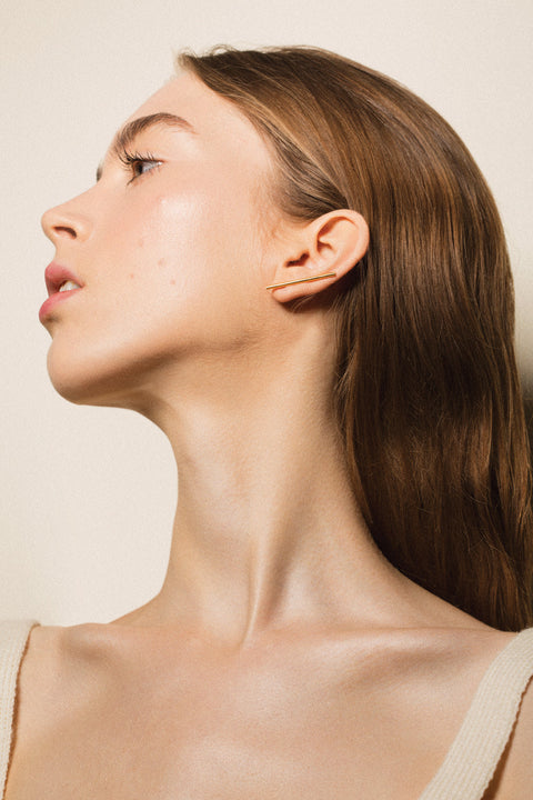Monolithic earrings featuring a tubular form and fine threader wire, designed for versatile styling. Wear them as a sleek line along the earlobe or as a dangling accent. A sculptural, minimalist piece that combines modern design with effortless adaptability. Discover contemporary jewelry by UMIAR jewelry.