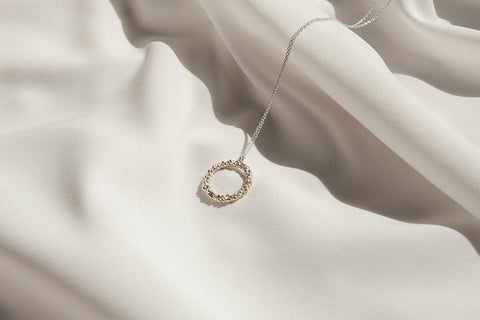 A circular pendant symbolizing perfection, crafted with a granulated, speckled silver texture inspired by the full moon. Suspended on a 50 cm silver chain, it works beautifully as a daily talisman or an elegant evening accessory. Discover cosmic elegance and timeless design by UMIAR jewelry.