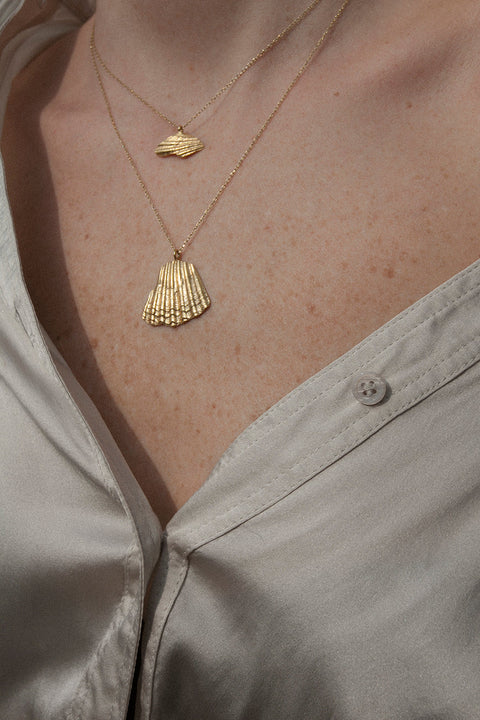 A delicate pendant inspired by the form of a broken shell, measuring 10 x 20 mm and suspended on a 40 cm chain. Combining organic texture with minimalist abstraction, this necklace captures timeless marine elegance. Ideal for summer looks and layering with the MARE II pendant. Discover refined seaside design by UMIAR jewelry.