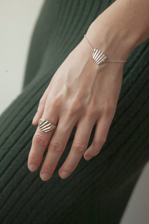 A square signet ring featuring an embossed shell motif that evokes the essence of summer by the sea. With a 12 × 12 mm face, it blends timeless form with a distinctive decorative touch. Perfect worn alone or stacked, and an ideal gift for birthdays, anniversaries, or engagements. Discover refined summer elegance by UMIAR jewelry.